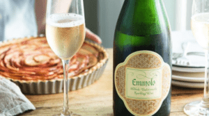 a bottle of Emmolo Sparkling wine on a table with a pie in the background