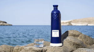 bottle of tequila komos placed on the shore of a body of water