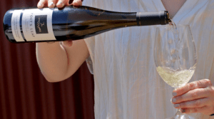 woman pouring a glass of Poet's Leap Botrytis Riesling into a glass of wine
