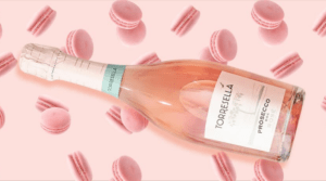a bottle of torresella prosecco rose on a patterned pink background with pink macroons